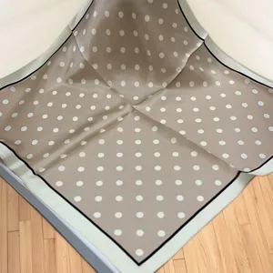 Close-up detail of the elegant polka dot silk square scarf, showing fine texture and smooth drape.