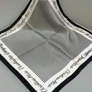 Detailed shot of black and white houndstooth silk square scarf with classic border text.