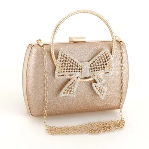 Elegant gold glitter evening clutch bag with sparkling rhinestone bow and metal handle detail