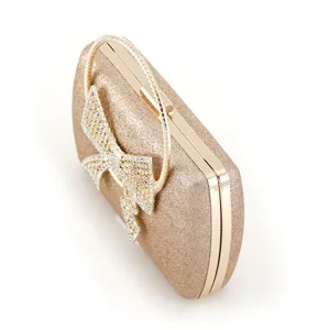 Detailed view of glamorous gold glitter evening clutch bag with sparkling rhinestone bow.