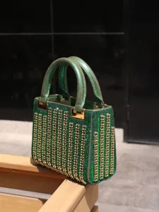 Close-up of luxury green rhinestone evening handbag with sparkling crystals and gold hardware details.