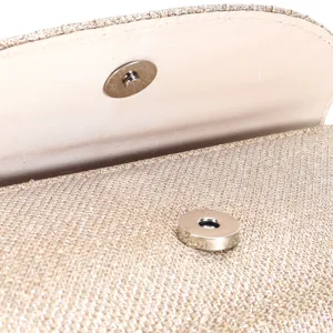 Detailed view of the gold glitter evening bag magnetic clasp, showing texture and hardware.