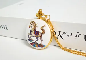 Pocket watch detail, gold metal case, white dial with colorful painted horse and chain.