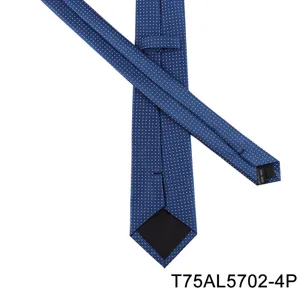 Detail view of men's blue formal jacquard tie with white geometric dots and handmade label.