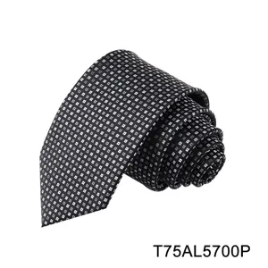 Detailed close-up view of the black and grey geometric patterned silk tie, neatly rolled up.
