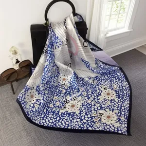 Luxurious silk square scarf with elegant blue floral print, smooth and soft styling accessory.
