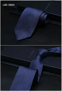 Close-up detail of dark blue silk jacquard tie featuring elegant silver polka dots and fine texture.