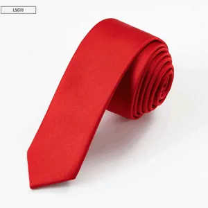 Detailed shot of a sleek red skinny necktie rolled up neatly, showing smooth fabric texture.
