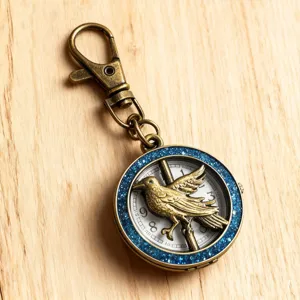Vintage bronze pocket watch keychain with mockingjay bird design and blue glitter accent for daily use.