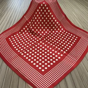 Close-up detail of the elegant red square silk scarf featuring a classic white polka dot pattern.