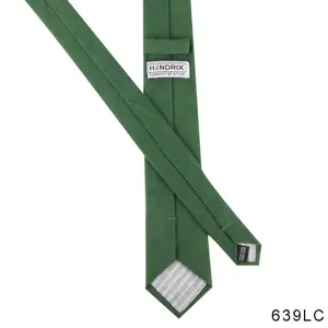 Detail shot of green linen mens tie showing brand label and handmade material tag clearly.