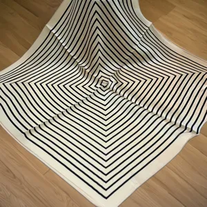 Detail view of a black and white geometric silk square scarf, elegant neck and bag accessory.