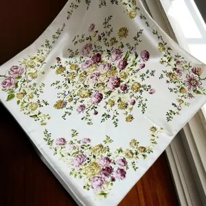 Detail shot of elegant white silk square scarf featuring delicate purple and yellow floral prints.