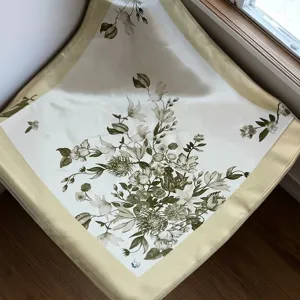 Close-up detail of botanical floral print silk square scarf with pale yellow border.