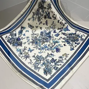 Close-up detail of a blue and white silk square scarf with elegant floral patterns.