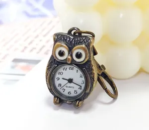 Detailed close-up shot of the antique bronze owl pocket watch dial and keychain clasp hook.