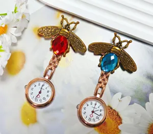 Detail view of alloy bee nurse pocket watch with red and blue crystals and quartz movement.