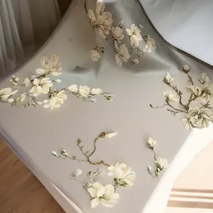 Close-up detail of mulberry silk square scarf featuring elegant magnolia floral print design.