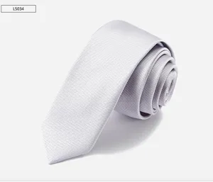 Close-up of a stylish light grey narrow men's tie with fine twill texture and 6cm width. Detail view.