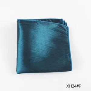 Detailopname van een opgevouwen heren pochet in turquoise glanzende stof met stiksels.