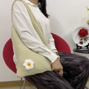 Detailansicht einer gestrickten Schultertasche mit niedlicher handgemachter Wollblume.