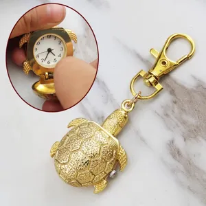 Detail view of the gold-plated turtle pocket watch keychain showing open dial features.