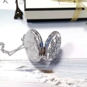 Orologio da tasca vintage in argento traforato con incisione floreale e lunga catena.
