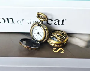 Detailed close-up of a vintage bronze zodiac pocket watch with hollow carved animal design.