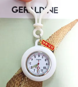 Close-up detail of white silicone fob nurse watch with clip and red lucky charm pendant.