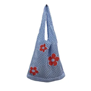 Nahaufnahme des stilvollen blauen Strick-Netzbeutels mit niedlichen roten Blumenmustern.