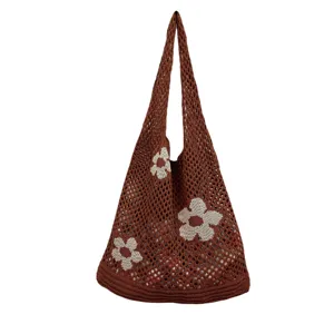 Detailansicht der braunen Strick-Häkel-Tasche mit weißen Blumenmustern und Netz-Design.