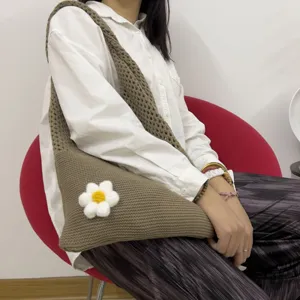 Detailansicht der braunen gestrickten Umhängetasche mit weißer Blume für den Alltag.