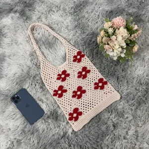 Detailed view of beige crochet floral tote bag with red flowers on a fluffy rug background.