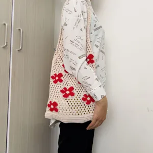 Detail view of the beige crochet knit tote bag featuring vibrant red floral pattern design.
