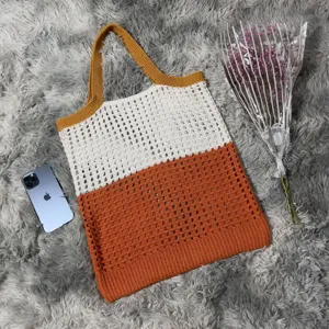 Detailansicht der stylischen farbblockgestrickten Tasche mit Netzstruktur und Henkel.