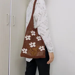 Detail view of the brown crochet shoulder bag featuring white knit flower patterns and hollow design.