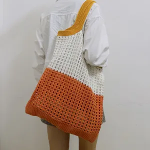 Detailansicht der gestrickten Damen-Farbblock-Hohltasche über der Schulter getragen.