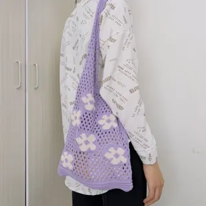 Detail view of a purple crochet knit shoulder bag with white flower patterns, casual style.