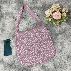 Nahaufnahme einer lila gestrickten Umhängetasche mit stilvollem geometrischem Rautenmuster.