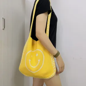 Nahaufnahme der gelben Strick-Tote-Bag mit einem süßen weißen Smiley-Muster Detail.