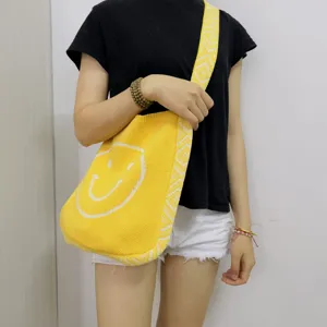 Charmante gelbe Strick-Umhängetasche mit einem süßen weißen Smiley-Muster und Webgurt.