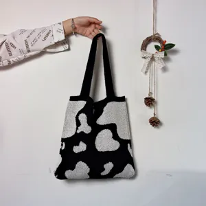 Détail de sac cabas en tricot imprimé vaches noir et blanc, sac bandoulière tendance mode.
