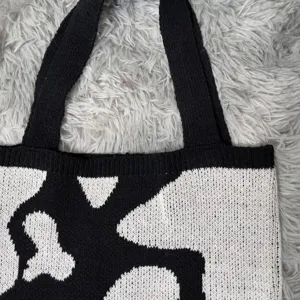 Vue détaillée d'un sac cabas en tricot noir et blanc élégant avec motif et poignées confortables.