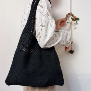 Nahaufnahme einer schwarzen Strick Shopper Tasche über der Schulter mit strukturierter Webart.