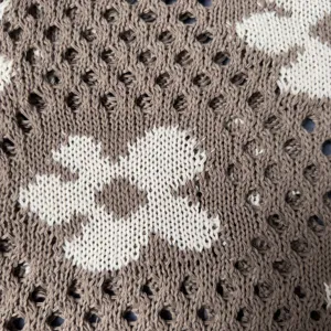 Detailed shot of the stylish hollow knit tote bag with beautiful flower pattern and soft woolen texture.
