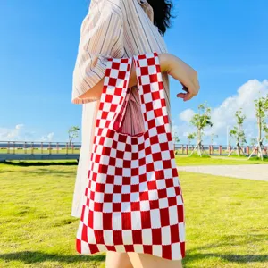 Detailaufnahme einer rot-weißen karierten Stricktasche im Freien, lässig und praktisch.