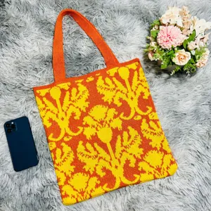 Nahaufnahme der gestrickten Blumentasche in leuchtendem Orange und Gelb mit feiner Webstruktur.