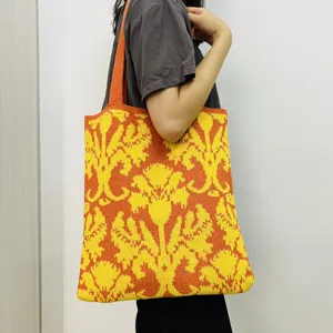 Detailansicht der stilvollen gestrickten Blumentasche in leuchtendem Orange und Gelb am Modell.