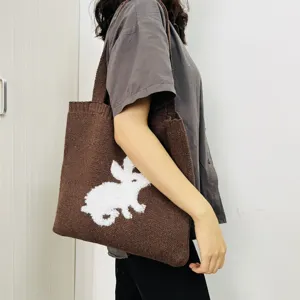 Bruine gebreide schoudertas shopper voor dames met schattig wit pluizig konijn patroon retro stijl.