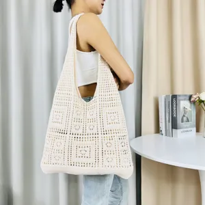 Detailansicht einer beigen Strick Häkel Tote Tasche mit feiner Lochmuster Textur und Henkel.